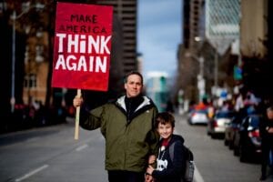 A proud father and son hold a sign calling for America to think again. An appropriate response for, among other things, Trump's tragic legacy of environmental deregulation.